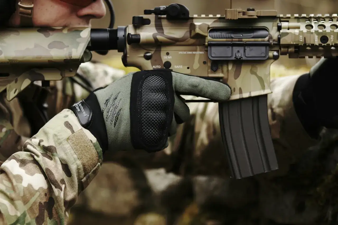 Ręka w rękawicy taktycznej celuje z repliki ASG. Jak zacząć przygodę z airsoftem?