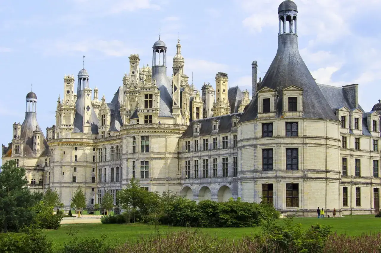 Le château de Chambord, un chef-d'œuvre de la Renaissance, se dresse majestueusement sous un ciel bleu. Ses tours et sa façade témoignent d'une époque révolue.