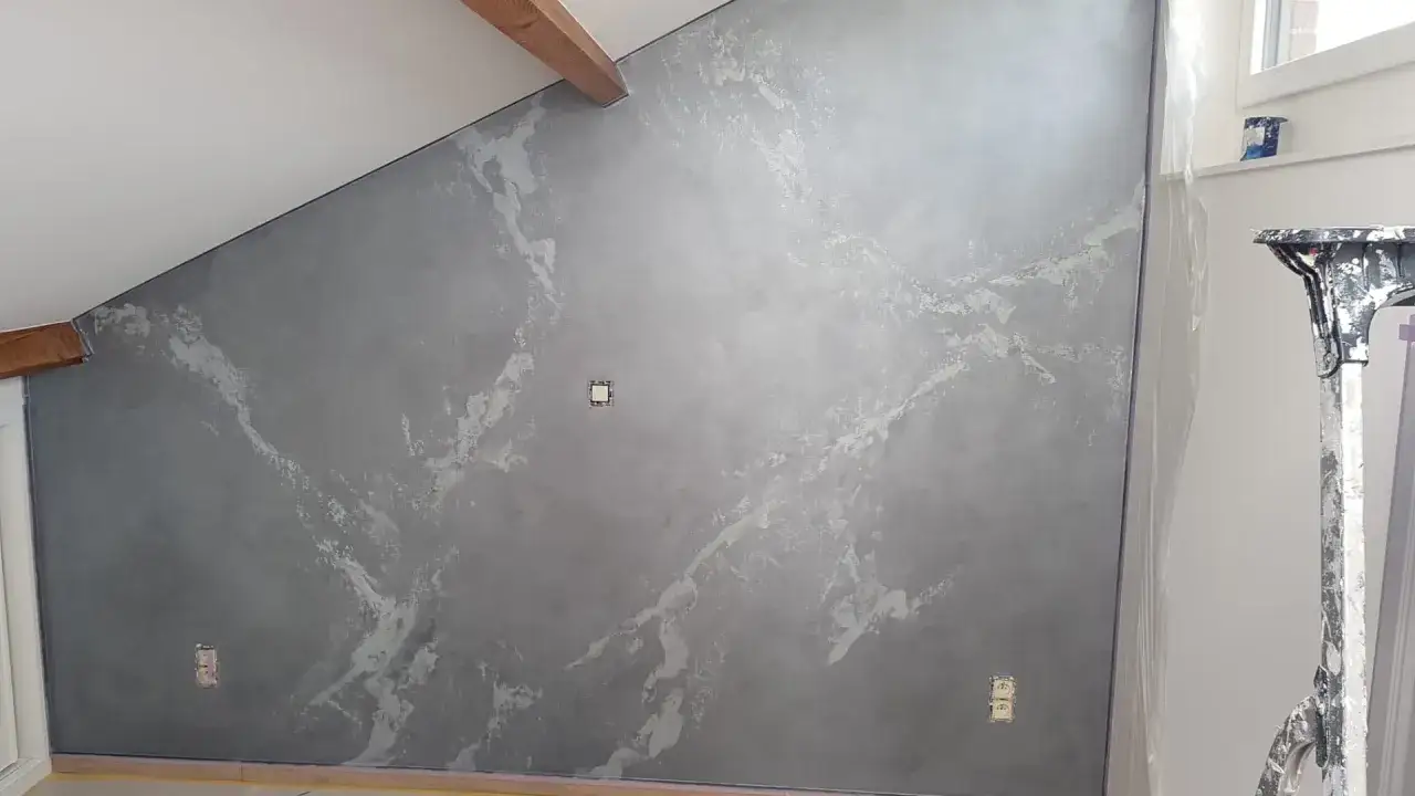 Mur gris avec un effet marbre obtenu par une **stucco peinture**. Des veines blanches et argentées traversent la surface, créant un rendu texturé et élégant.
