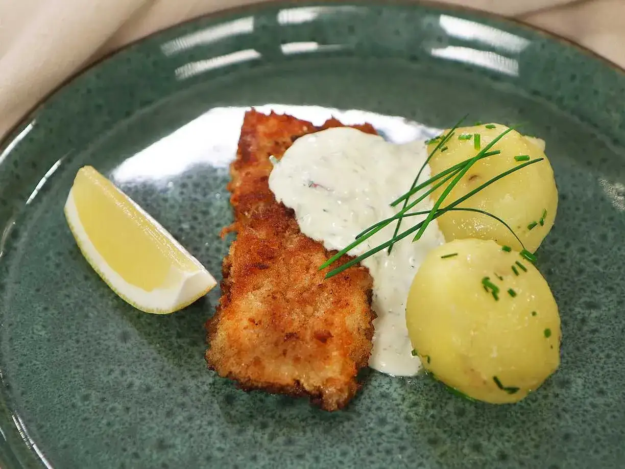 Panerad fisk med krämig remouladsås, kokt potatis och citronklyfta. En klassisk svensk rätt som smakar ljuvligt.