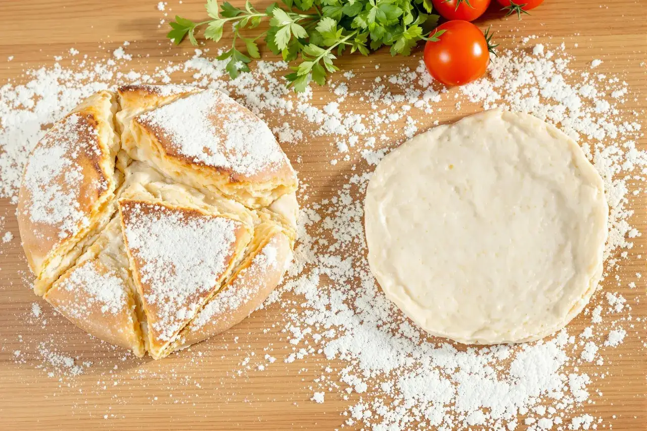 Pain dor&eacute; saupoudr&eacute; de sucre glace &agrave; c&ocirc;t&eacute; d'une p&acirc;te &agrave; pizza, avec des tomates et du persil. La farine de froment gluten est essentielle pour cette pr&eacute;paration.