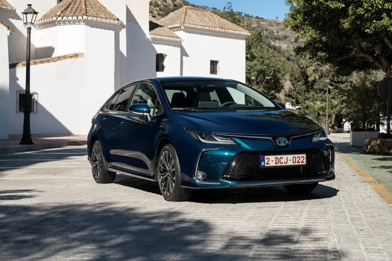 Ciemnoniebieska Toyota Corolla sedan na tle białych budynków. Poznaj jej wymiary i możliwości.