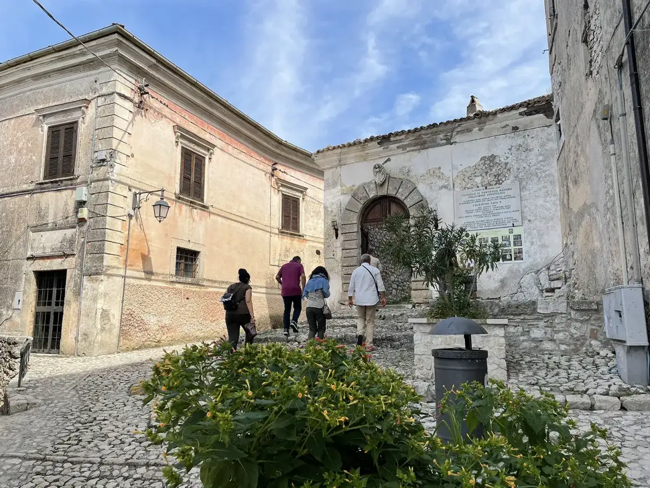 Un gruppo di turisti esplora un borgo ciociaro, tra i 5 borghi da visitare in Ciociaria. Le antiche case in pietra e il cielo azzurro fanno da cornice.