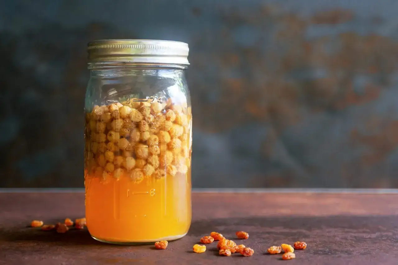 Glas mit s&uuml;&szlig;em Saft und Rosinen, bereit, um Hefe selber machen zu beginnen.