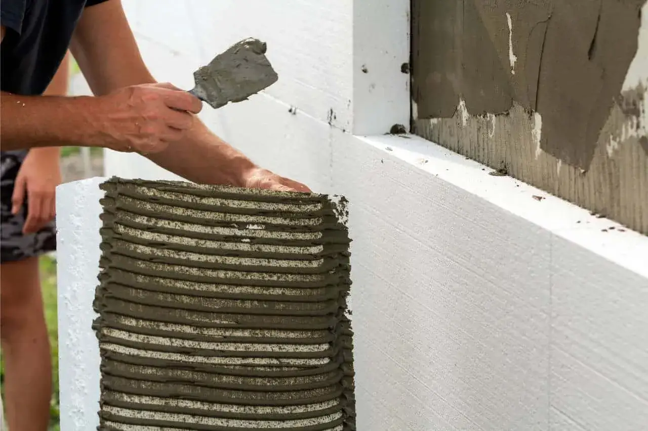 Un alba&ntilde;il aplica mortero a un bloque de poliestireno expandido, parte de un sistema de construcci&oacute;n que explica qu&eacute; es el sate.