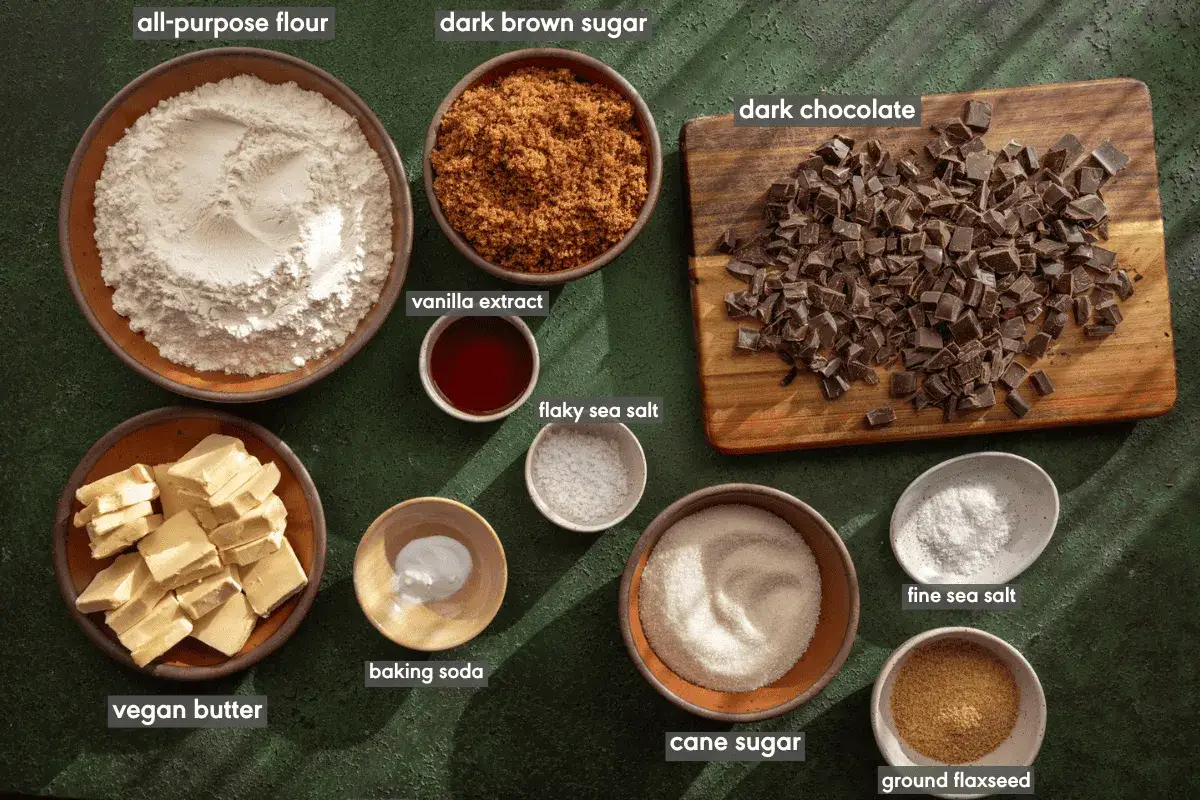 Zutaten für vegane Kekse: Mehl, brauner Zucker, vegane Butter, Schokolade, Vanilleextrakt, Backpulver, Salz und Leinsamen.