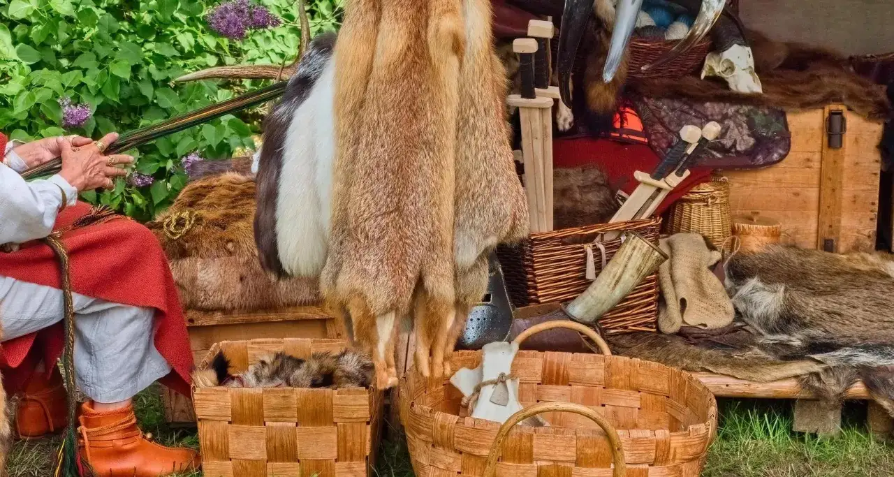 Frauen im Mittelalter bei einem Marktstand mit Fellen, H&ouml;rnern und Waffen.