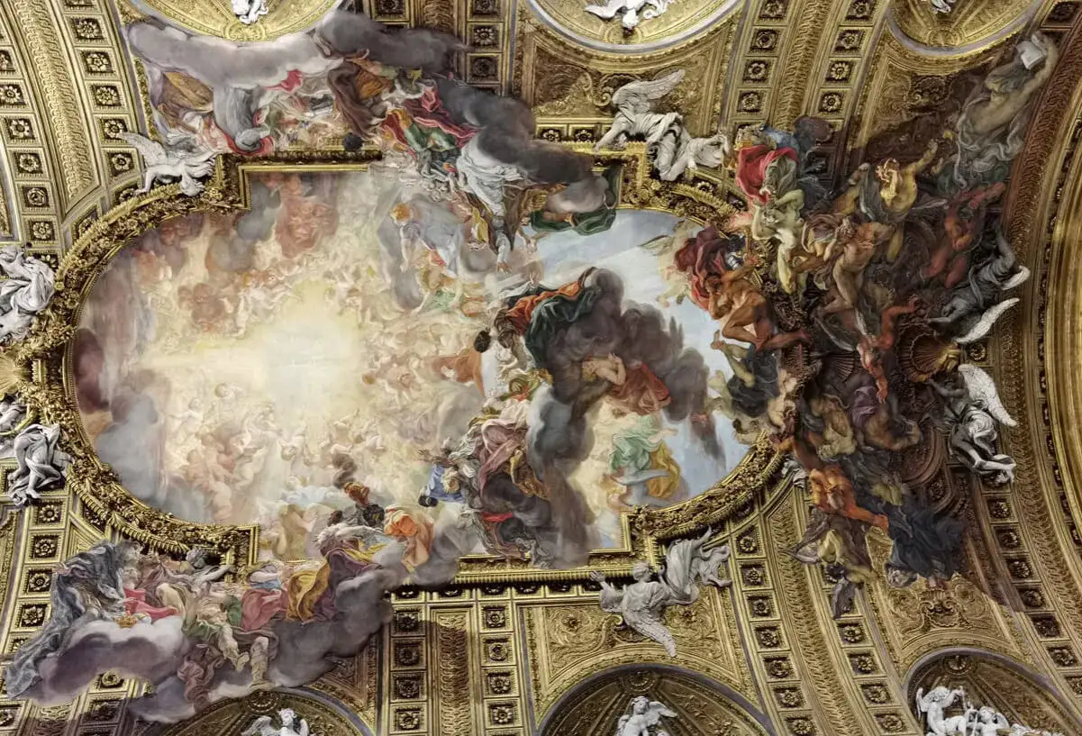 Soffitto affrescato della chiesa del Gesù, un tripudio di angeli e figure celesti che sembrano fluttuare tra nuvole dorate e scure.