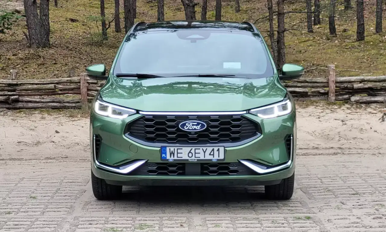 Zielony Ford Kuga 2019 z nowoczesnym grillem i światłami LED stoi na tle leśnej polany.