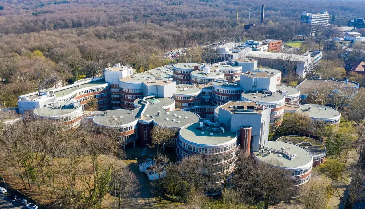 Luftaufnahme des Campus der Hochschule Essen mit seinen charakteristischen runden Gebäudeteilen, umgeben von Bäumen.