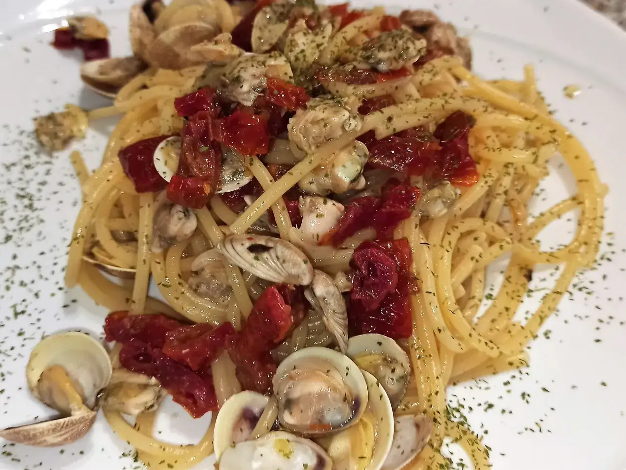 Spaghetti con lupini, pomodorini secchi e prezzemolo, un piatto di mare saporito e colorato.