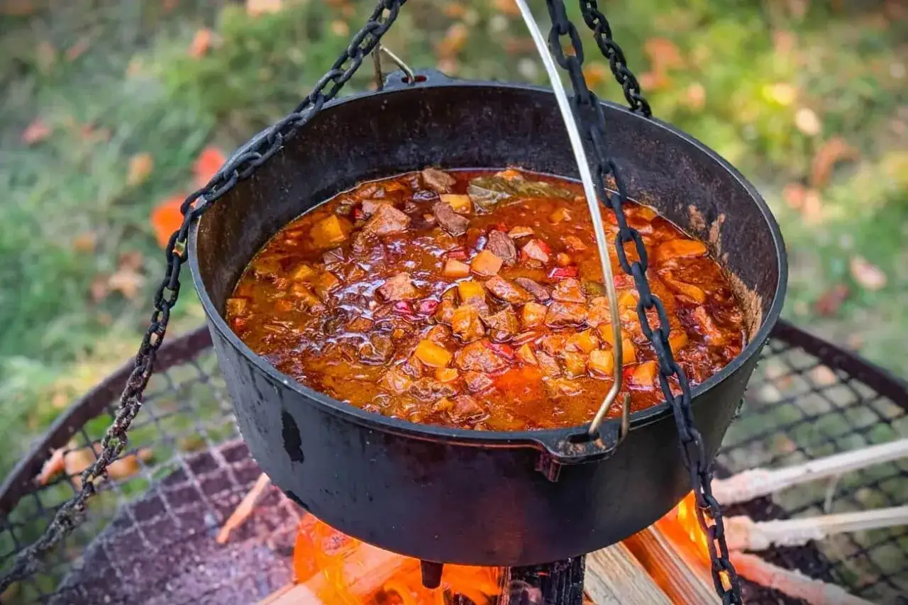 Herzhaftes Schweinegulasch kocht über offenem Feuer. Ein tolles Rezept für draußen!