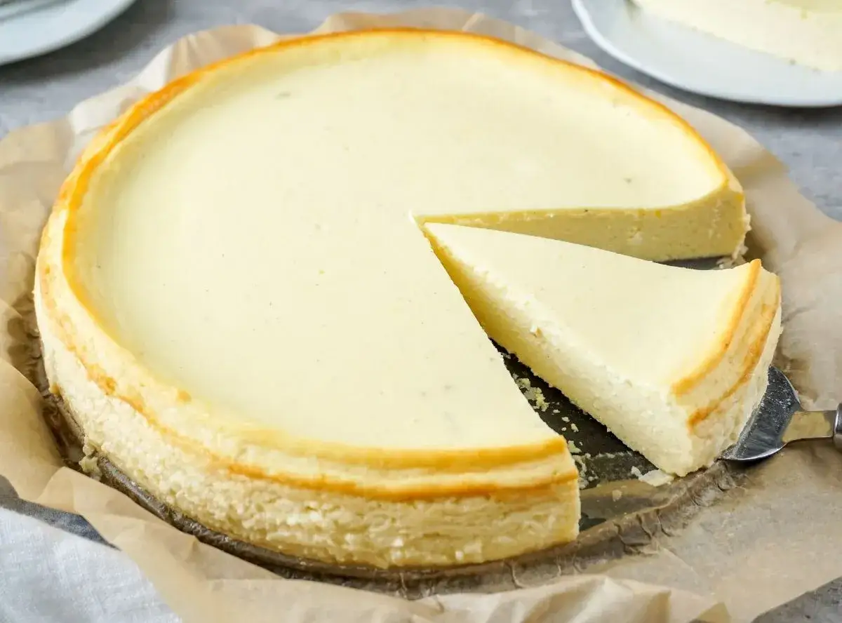Ein cremiger Quarkkuchen ohne Boden, mit einem Stück auf einem Tortenheber.