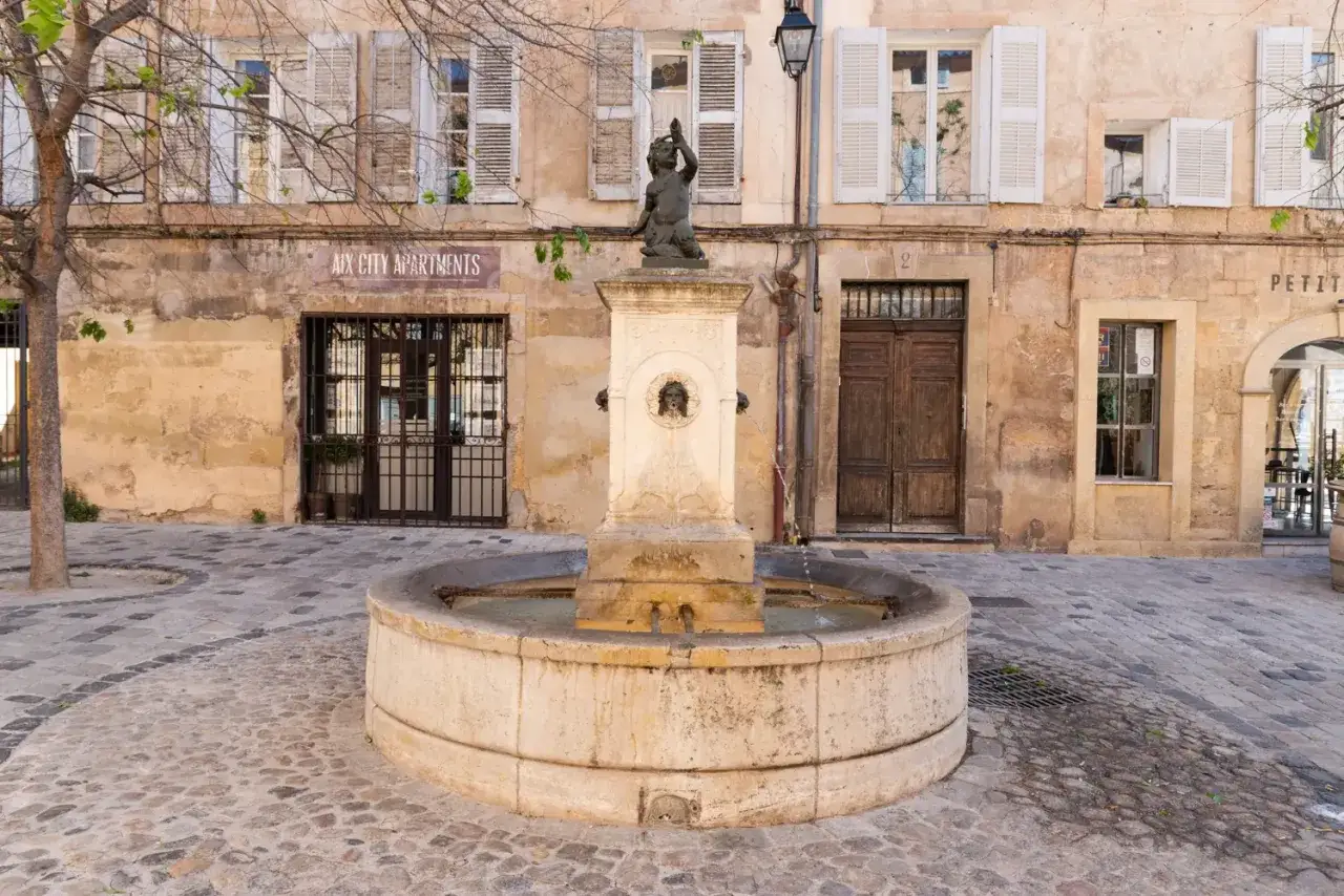 Fontaine et façade d'immeuble à Aix-en-Provence. Idéal pour visiter Aix-en-Provence à pied.