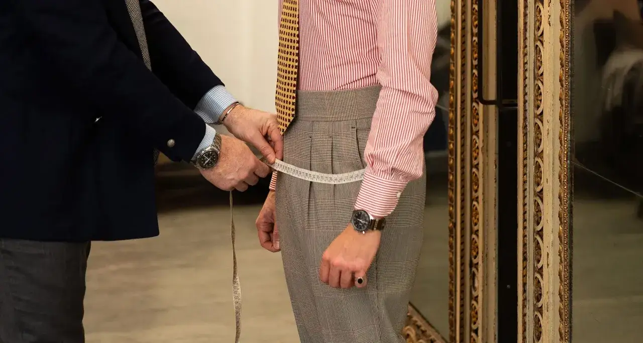 Sarto misura la vita di un cliente per capire come calcolare la taglia dei pantaloni.