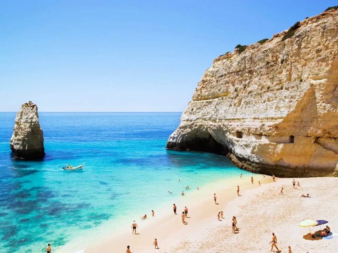Sonnige Bucht mit Felsen und Menschen am Strand. Perfekt für die beste Reisezeit Algarve.