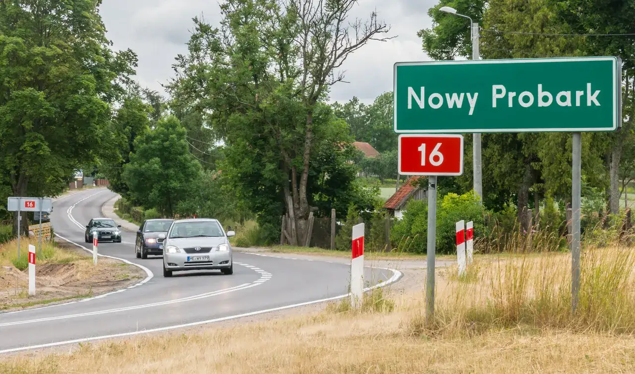 Droga krajowa 16 w Nowym Probarku. Samochody jadą krętą trasą wśród zieleni.