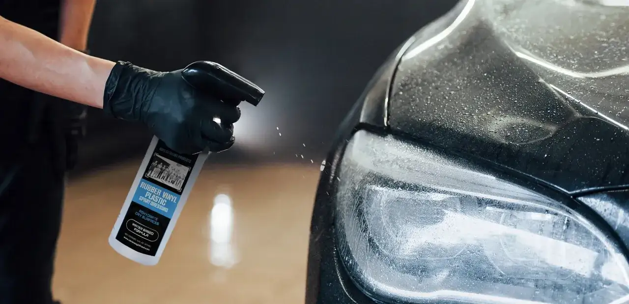 En hand med svart handske sprayar en bil med en produkt f&ouml;r gummi, vinyl och plast. VRP-formulan ger nytt liv &aring;t torra ytor.