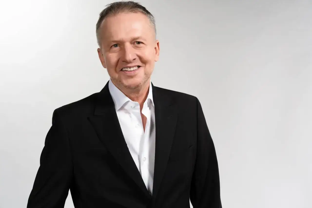 Uśmiechnięty mężczyzna w czarnym garniturze i białej koszuli. Zastanawiasz się, w jakich filmach grał Linda?
