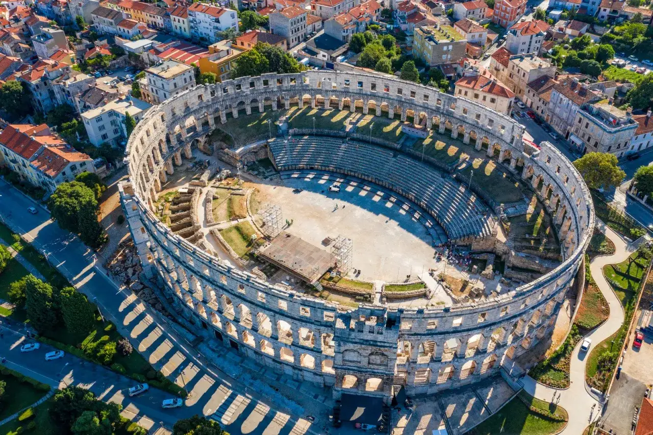 Starożytny amfiteatr w Puli, miasto w Chorwacji, otoczony budynkami i zielenią.