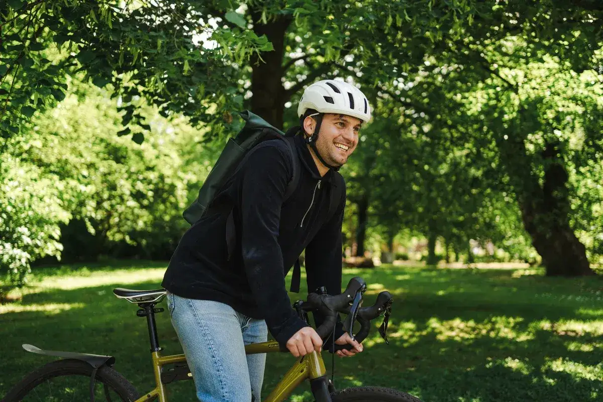 Glad man p&aring; cykel i parken, kanske med bidrag till elcykel.