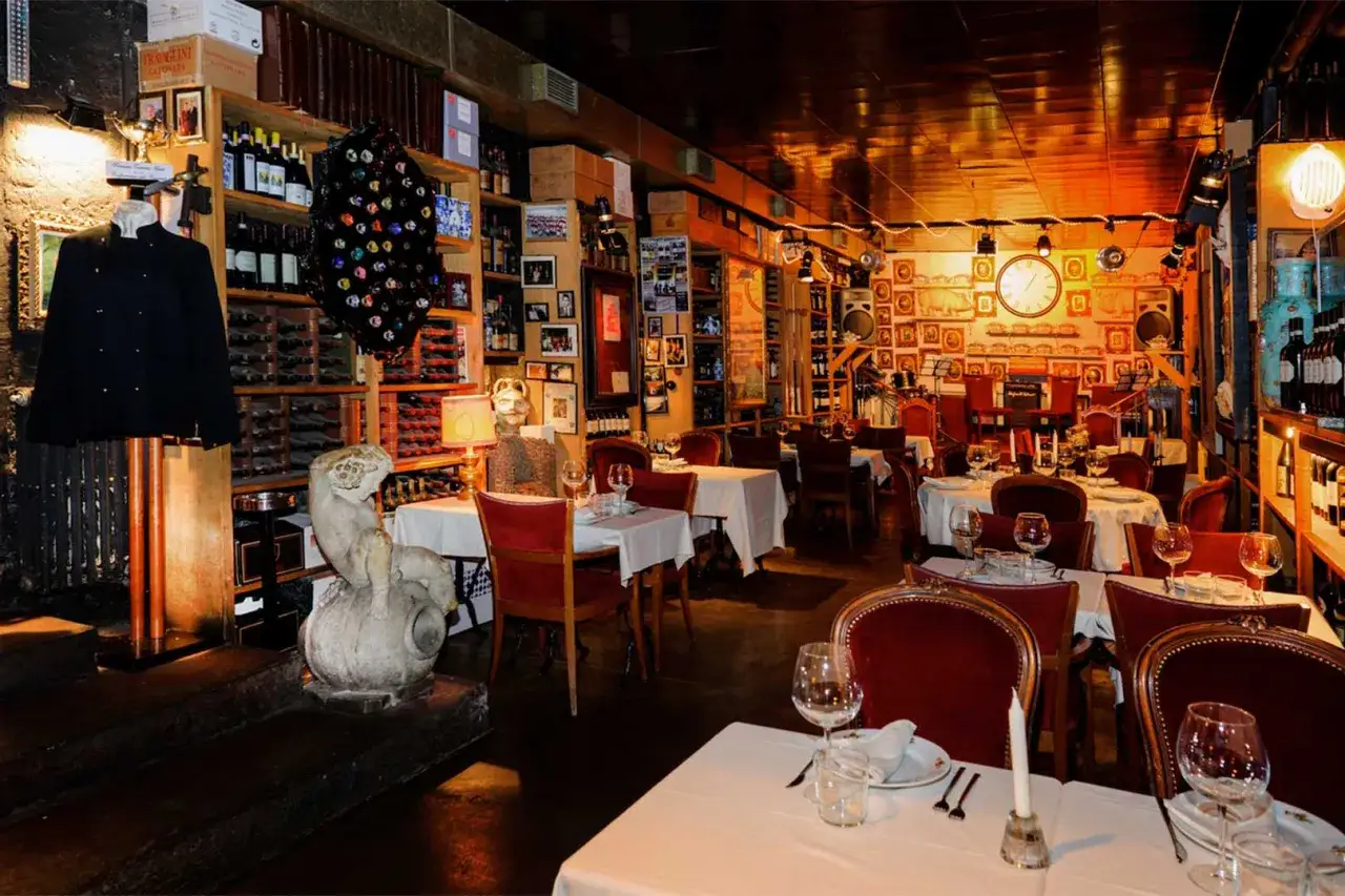 Atmosfera intima in uno dei **4 ristoranti milano**, con tavoli apparecchiati, bottiglie di vino e foto d'epoca alle pareti.