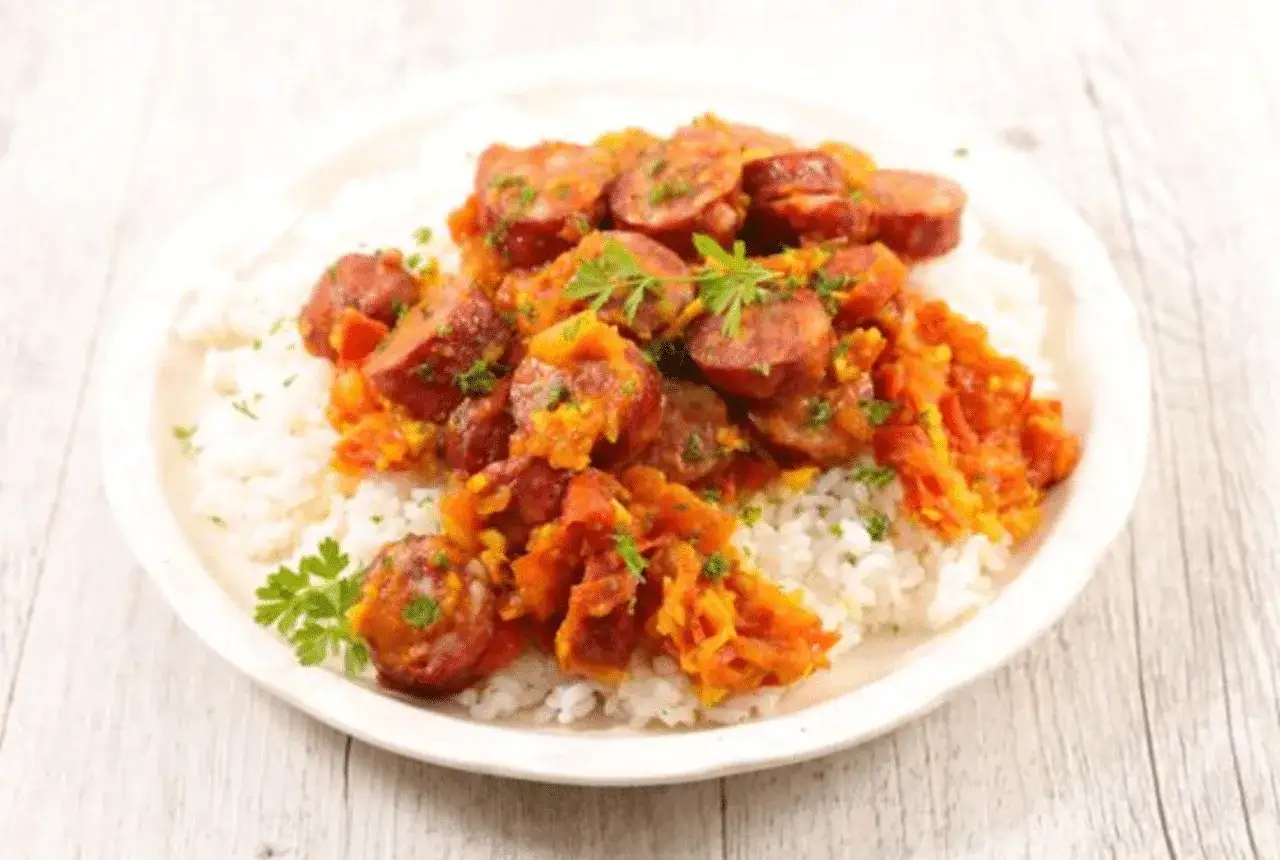 Un plat de rougail saucisse savoureux, avec des rondelles de saucisse &eacute;pic&eacute;e sur un lit de riz blanc, garni de persil frais.