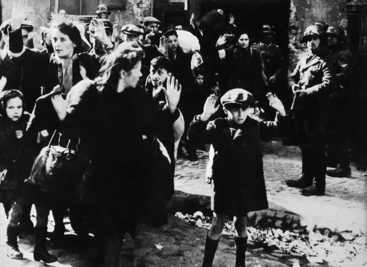 Una scena drammatica tra le foto celebri: civili con le mani alzate, alcuni bambini, circondati da soldati.