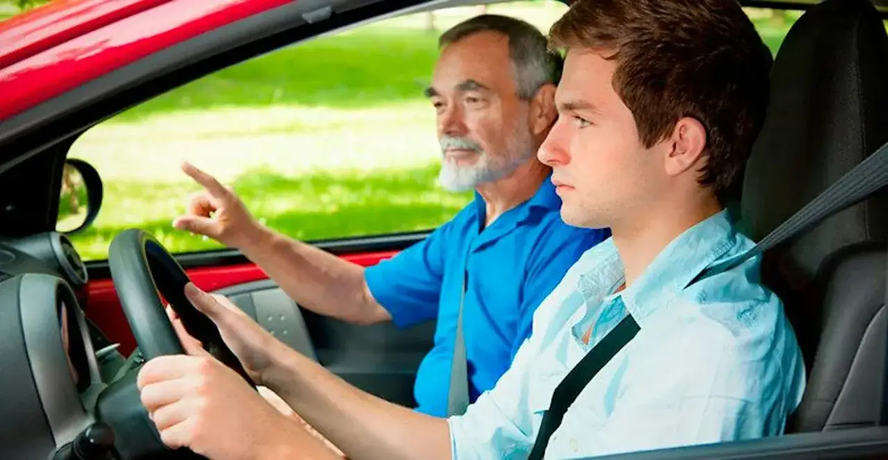 Un jeune homme apprend la conduite avec un moniteur expérimenté. L'instructeur montre la direction, guidant l'élève lors de cet entraînement conduite voiture.