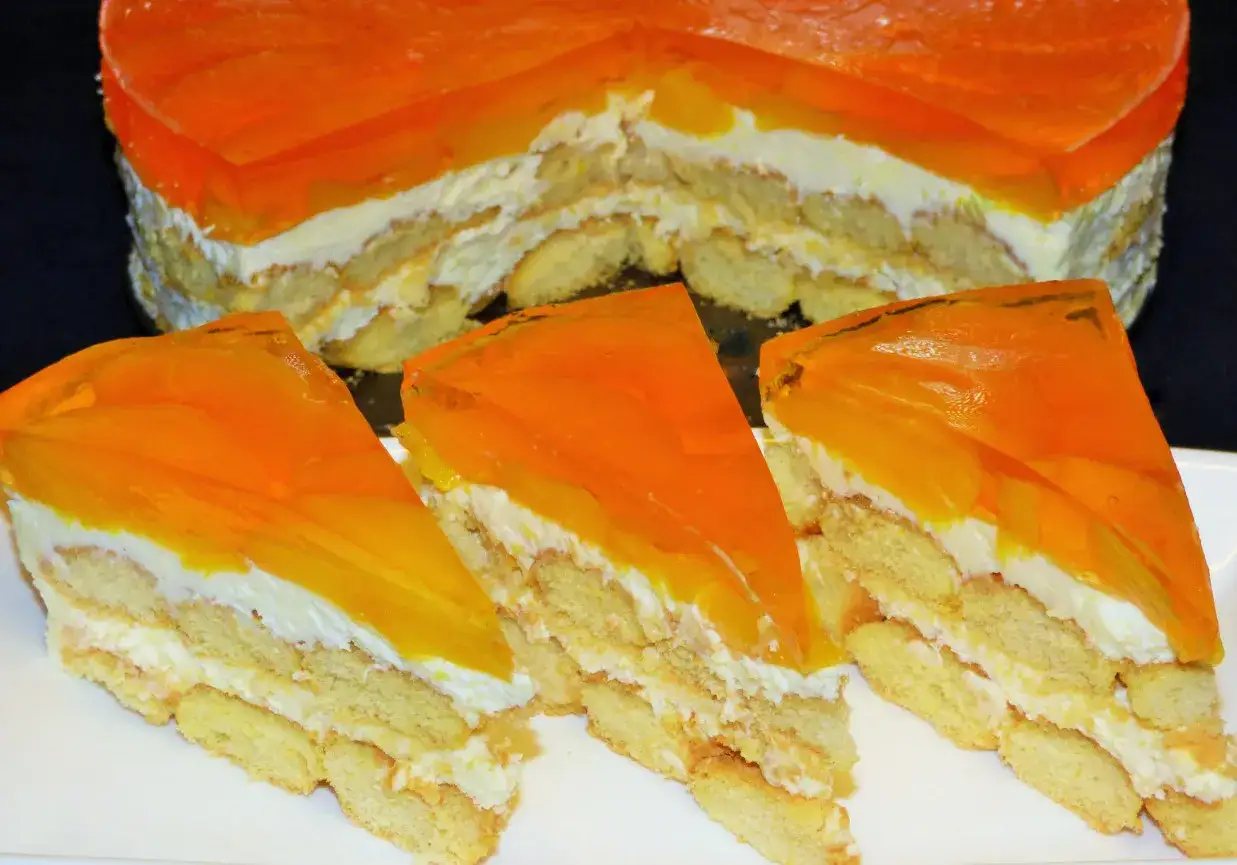 Pyszne ciasto z brzoskwiniami i mascarpone, z warstwami biszkoptów i kremu, pokryte pomarańczową galaretką.