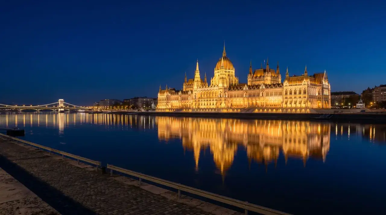 Budynek Parlamentu w Budapeszcie, stolicy Węgier, odbija się w spokojnej wodzie Dunaju nocą.
