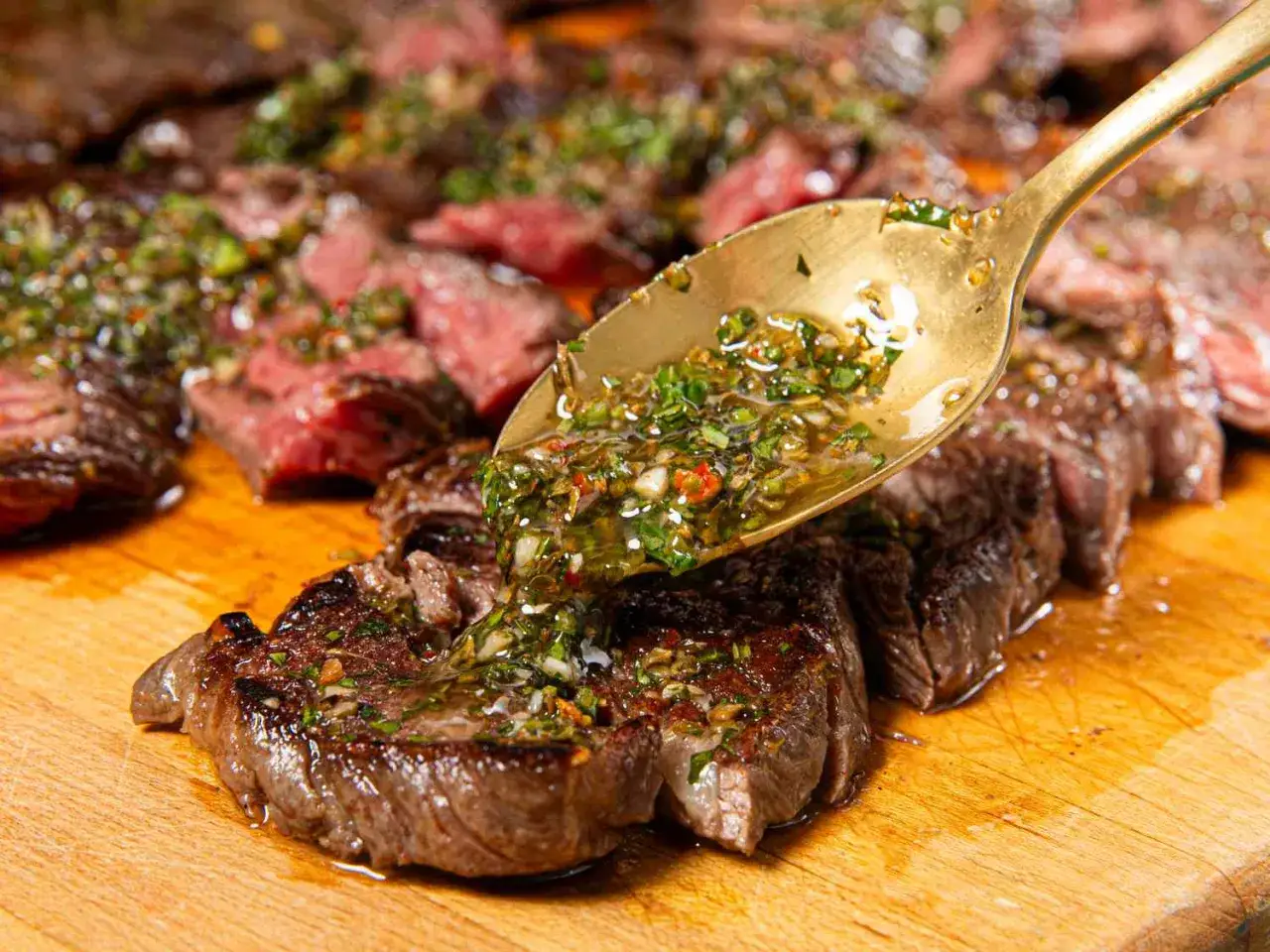 Cuillère dorée versant une sauce verte sur des tranches de filet mignon grillé. Un délice pour la marinade !
