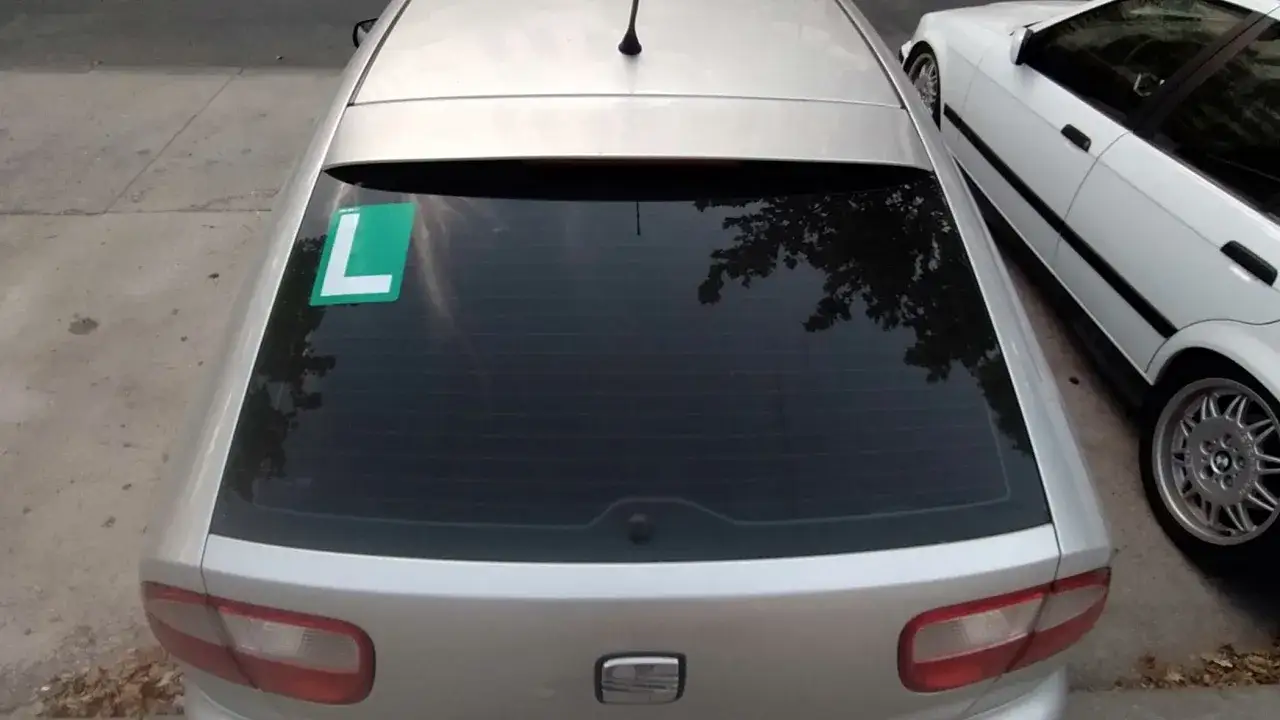 Un coche plateado tiene una pegatina verde con una 
