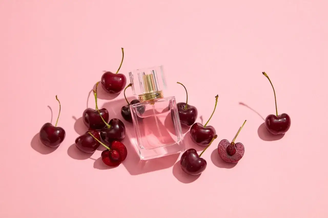 Szklana buteleczka z różowym płynem otoczona dojrzałymi wiśniami. Zapach niczym słodki, soczysty **cherry perfume**.