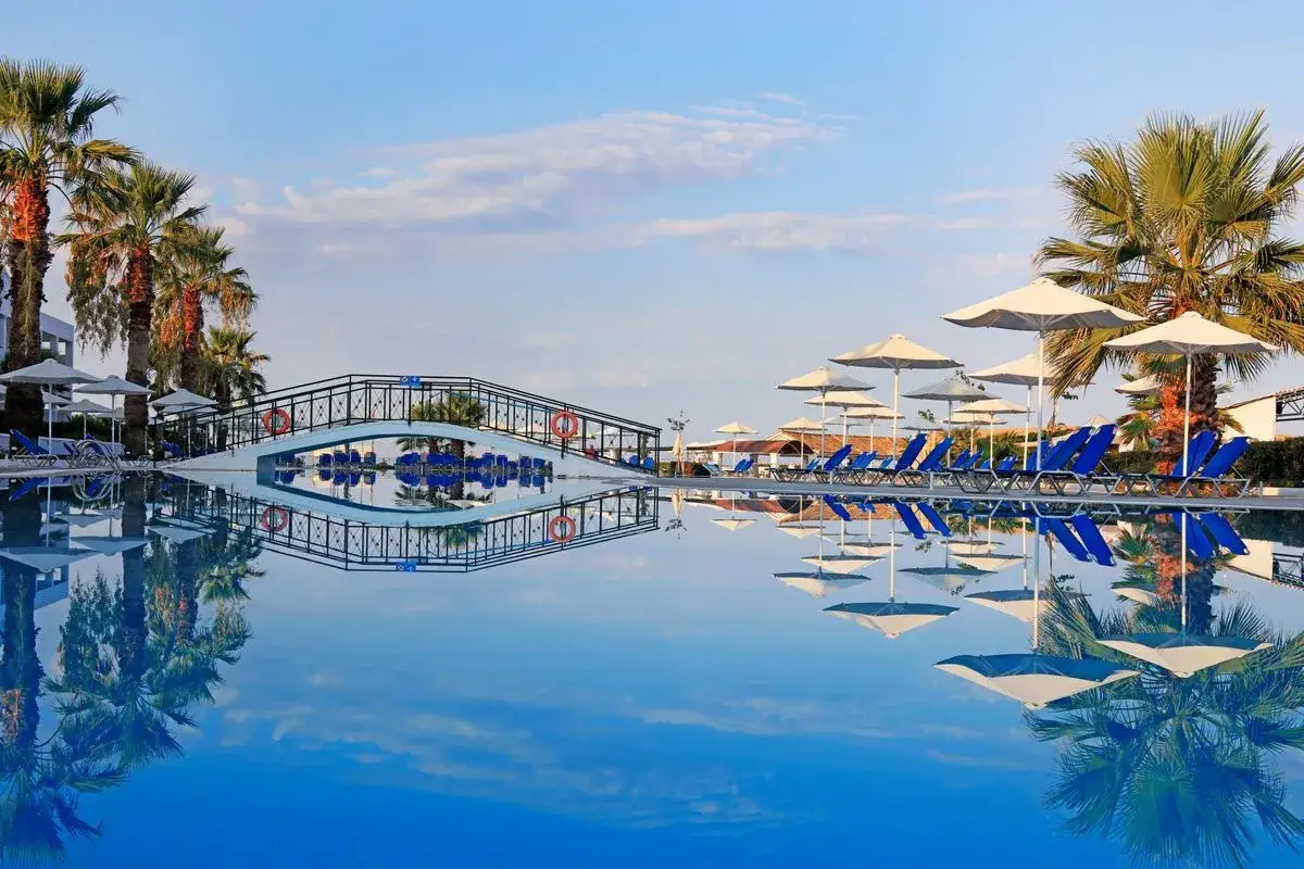Basen z odbiciem mostku i palm. Wiele leżaków i parasoli. Idealne miejsce na wakacje, jak sugerują labranda sandy beach resort opinie.