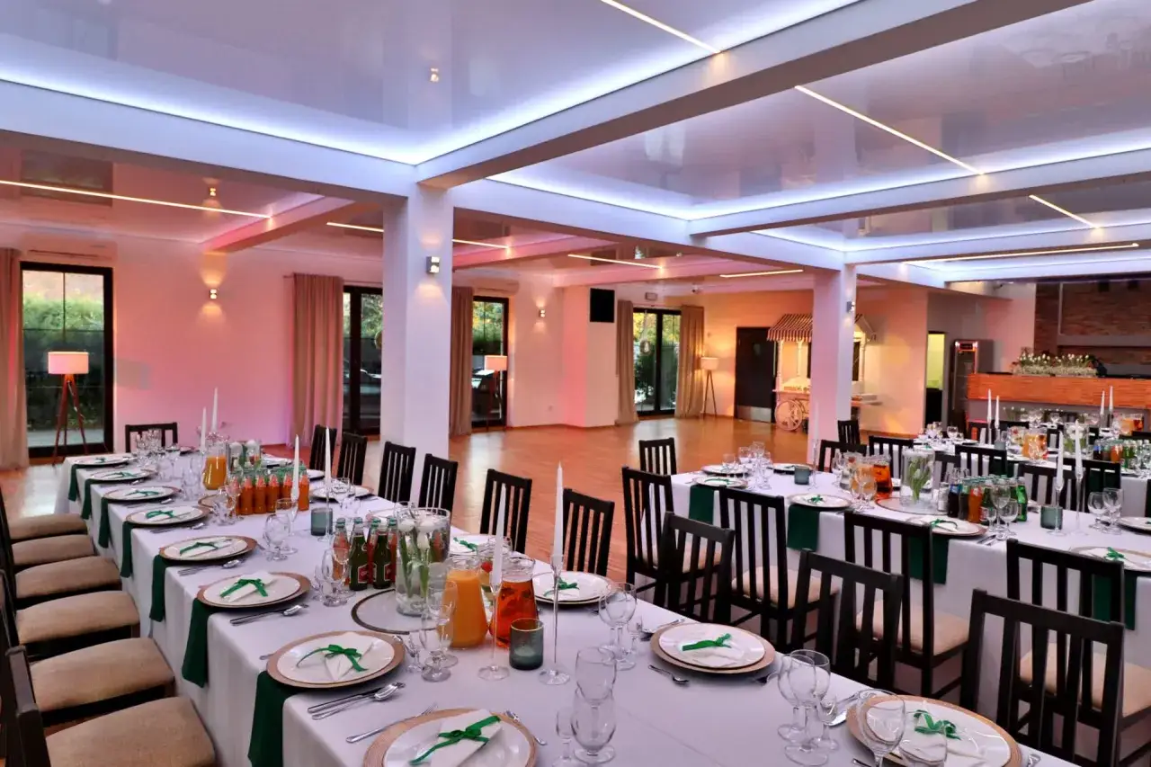 Elegancko nakryty stół z talerzami, szkłem i butelkami napojów, gotowy na przyjęcie. To idealne miejsce na wesele, gdzie każdy szczegół menu jest dopracowany.