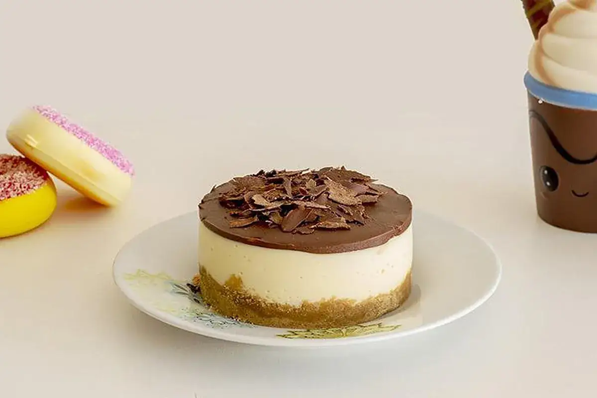 Mini cheesecake al cioccolato con base croccante, ricoperta da una ganache al cioccolato e scaglie di cioccolato fondente.