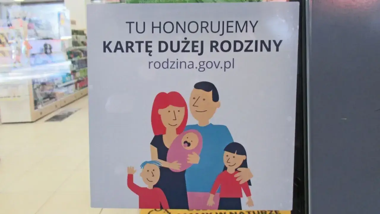 Plakat informuje o honorowaniu Karty Dużej Rodziny, prezentując uśmiechniętą rodzinę z dziećmi. Lista zniżek dla rodzin jest dostępna na rodzina.gov.pl.