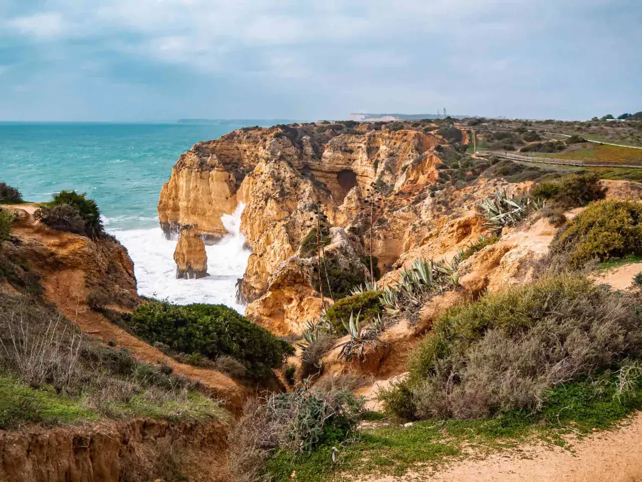 Rugged cliffs meet the turquoise sea, a dramatic landscape perfect for the best hiking in Portugal. Waves crash against sea stacks.