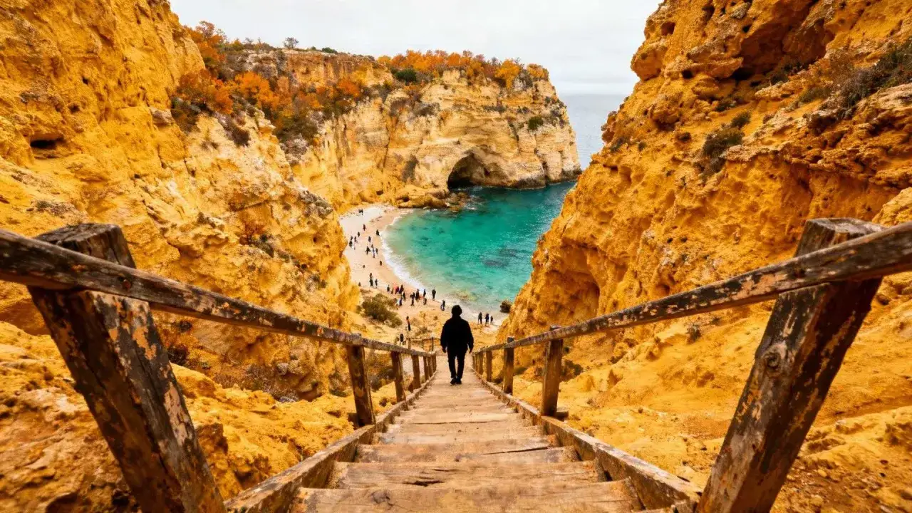 Holztreppe f&uuml;hrt hinab zum Praia do Carvalho, einer Bucht mit t&uuml;rkisfarbenem Wasser und goldenen Felsen.