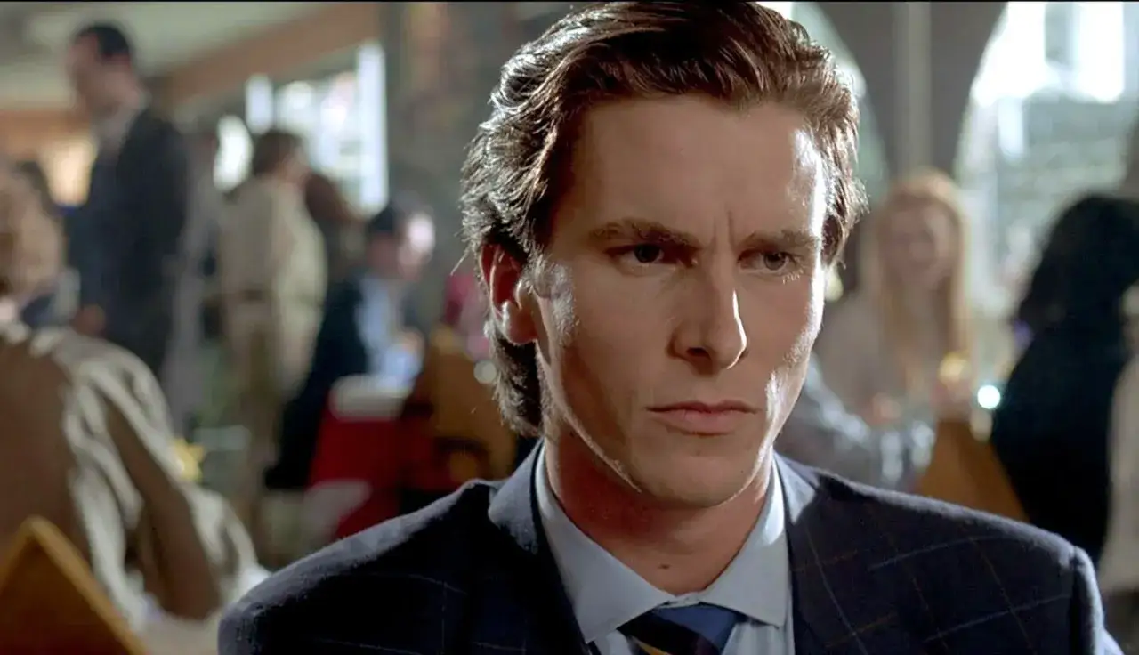 Christian Bale i en mörk kostym, med en intensiv blick. En scen från en av hans filmer, kanske American Psycho.