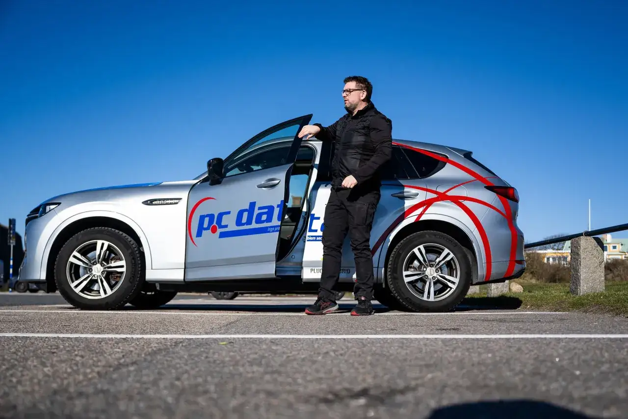 Man lutar sig mot en silverfärgad Mazda CX-60 laddhybrid med logotypen