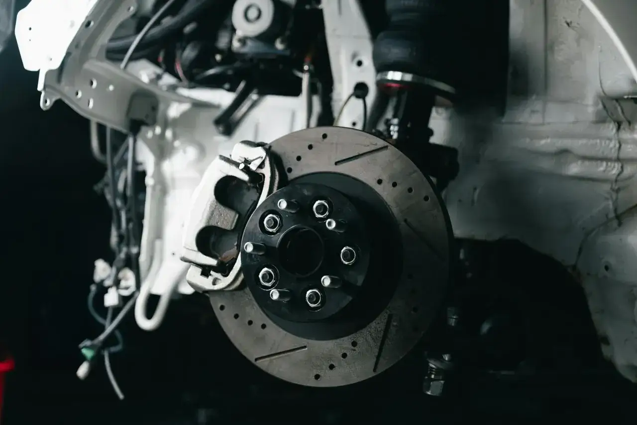 Widok z bliska na tarczę hamulcową i zacisk. Klocek hamulcowy nie odbija od tarczy, co może wskazywać na problem z układem hamulcowym.