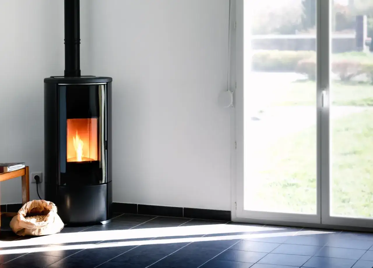 Stufa a pellet moderna con fiamma viva, sacco di pellet a terra. Ideale per capire quanto consuma stufa a pellet.