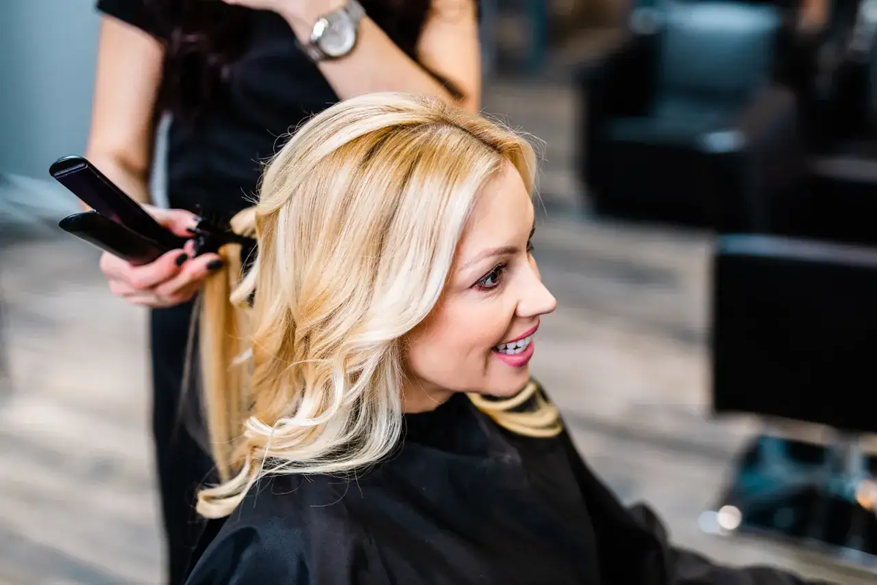 fryzjer stylizuje włosy klientki przed makijażem
