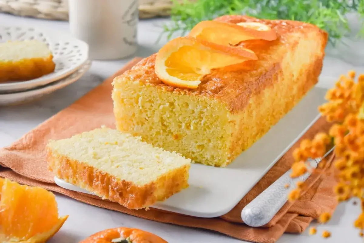 Un delicioso bizcocho de naranja, con rodajas de naranja fresca encima, listo para disfrutar.