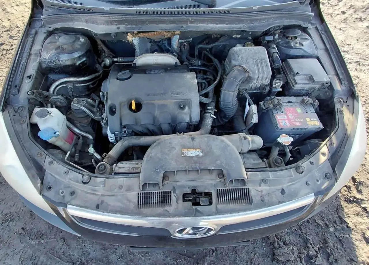 Silnik Hyundai i30 1.4 benzyna, widoczny pod maską, z akumulatorem i innymi elementami układu.