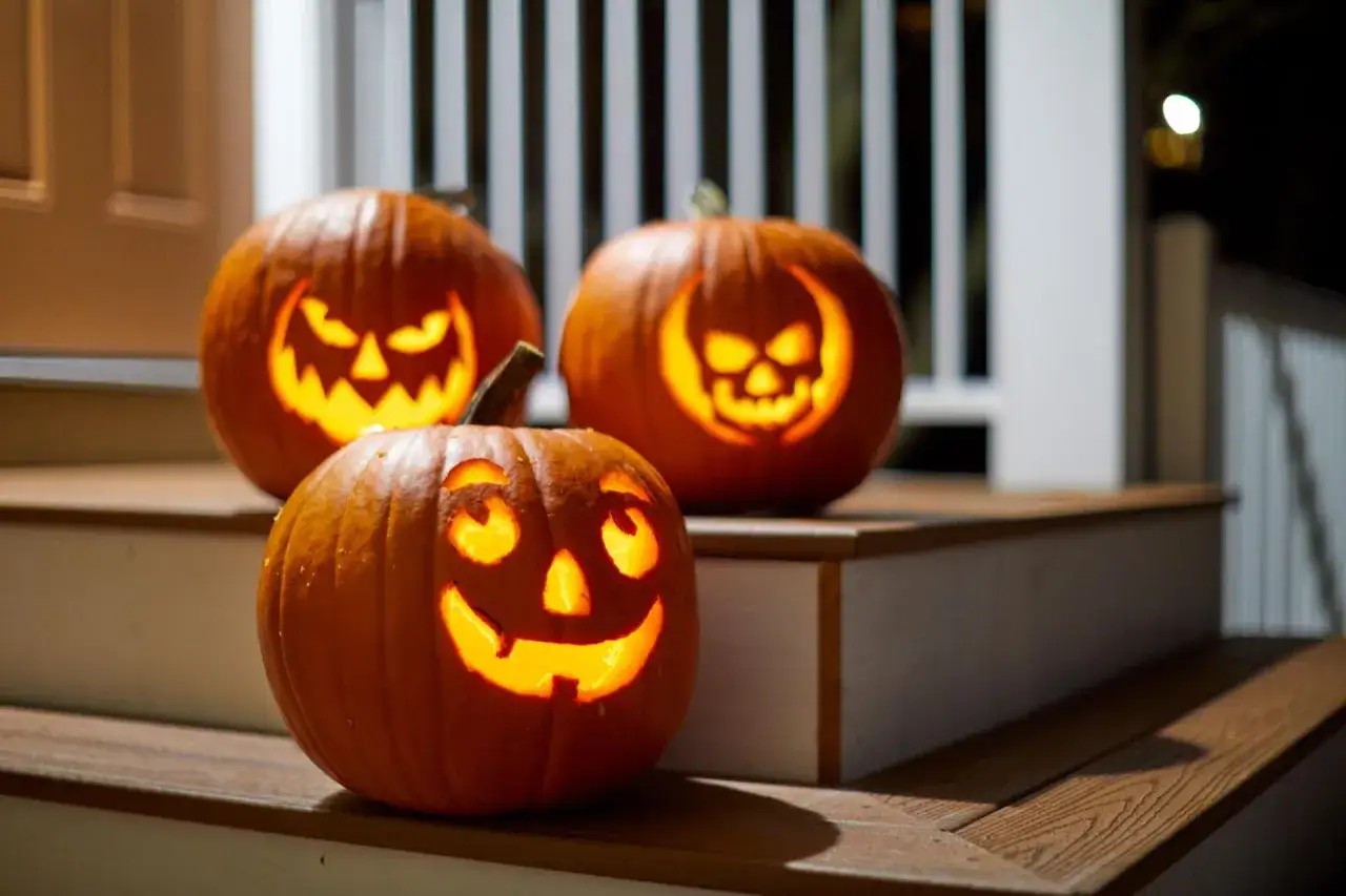 Trzy świecące dynie z wyciętymi strasznymi twarzami na schodach. Idealne ozdoby halloween jak zrobić.