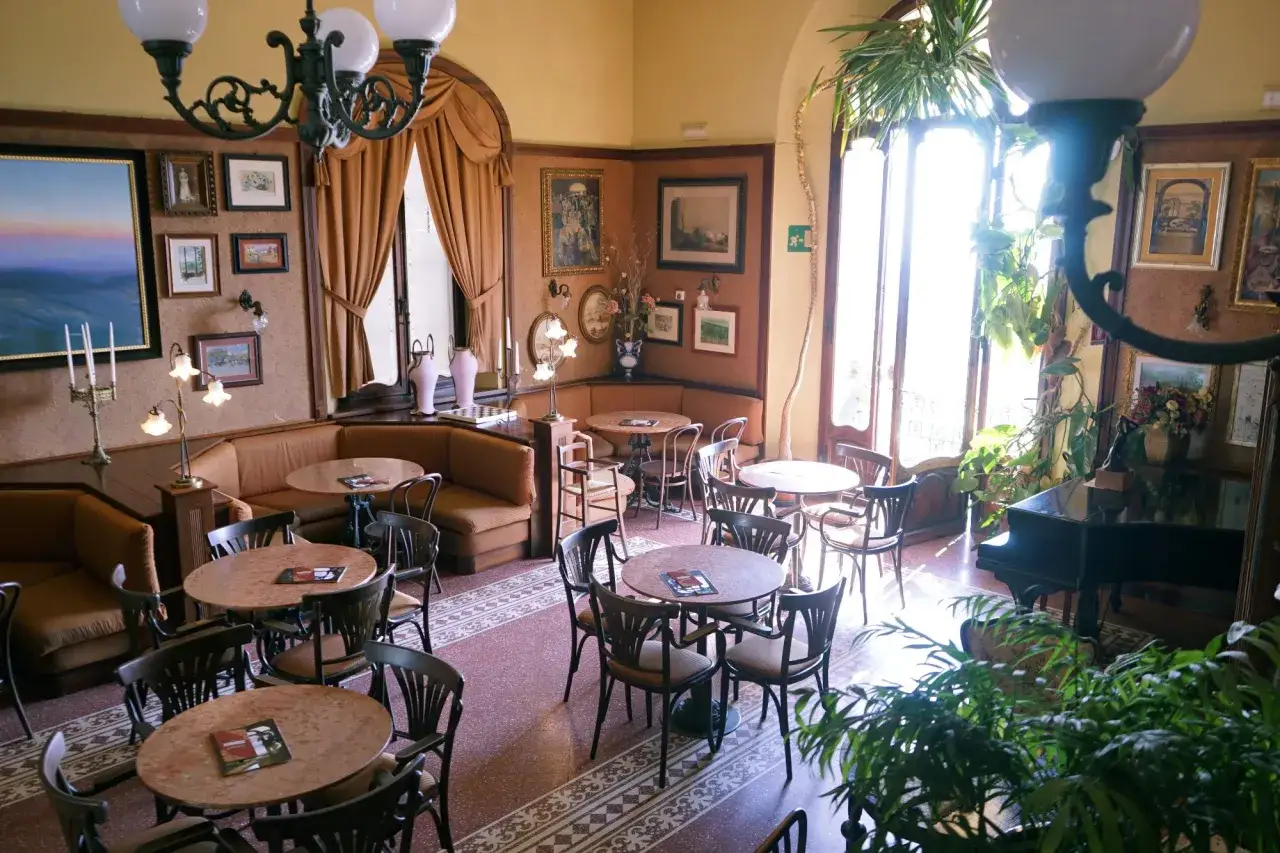 Atmosfera accogliente per scoprire dove mangiare a Montepulciano: tavolini, divanetti e un pianoforte in un locale elegante.