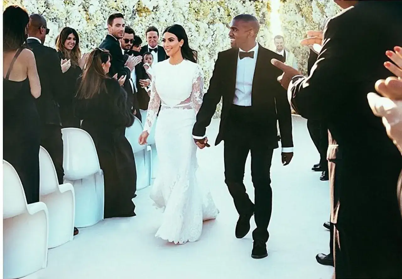 Kim Kardashian i jej mąż Kanye West idą razem, trzymając się za ręce, podczas ceremonii ślubnej.